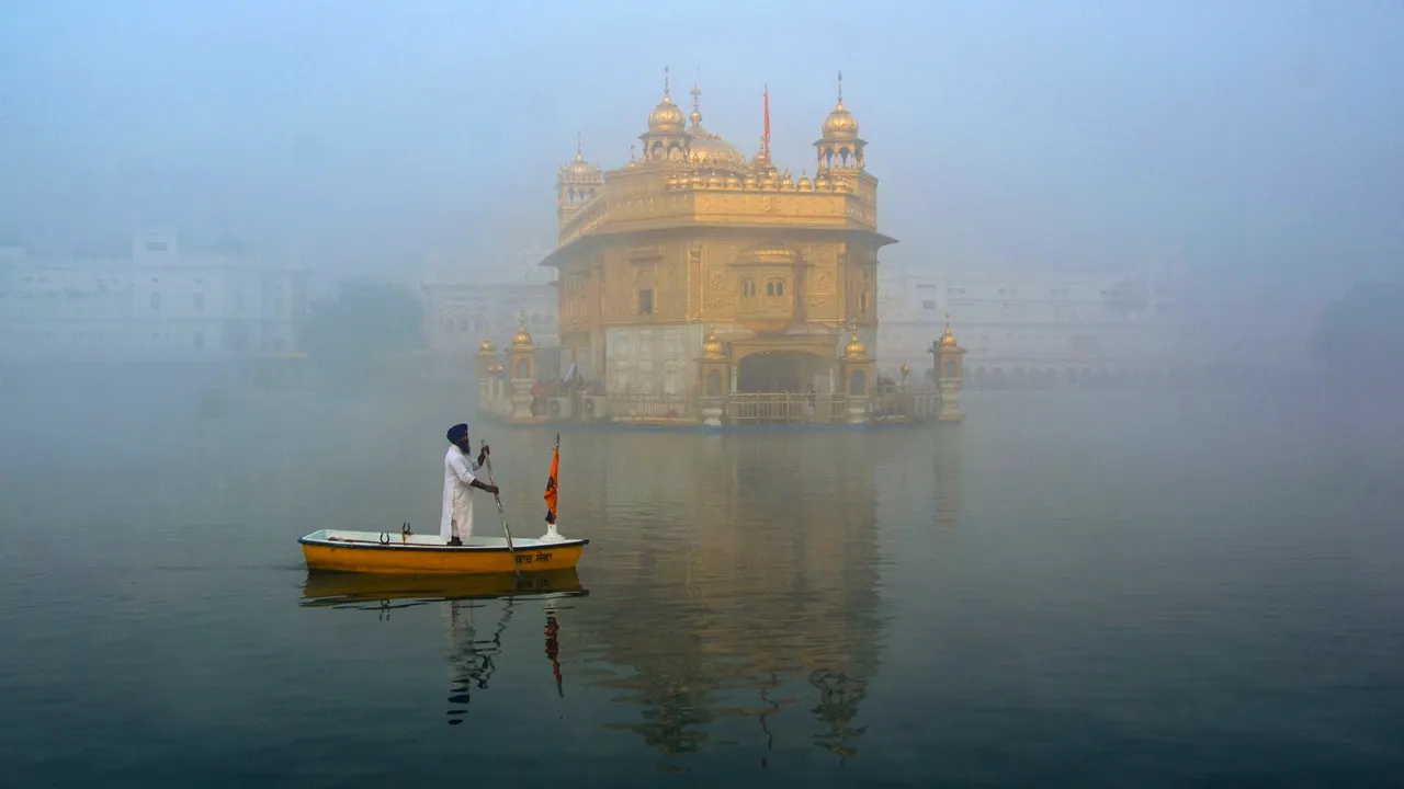 A 'sewadar' cleans the 'holy sarovar' at the Golden Temple amid fog, in Amritsar
