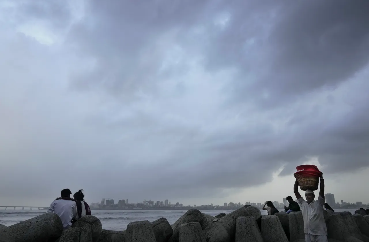 People visit the seafront as monsoon clouds cover the city skyline, in Mumbai