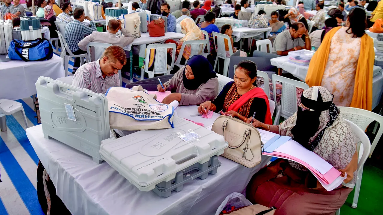 Polling officials collect EVMs and other polling materials on the eve of the Telangana Assembly election, at a distribution centre in Hyderabad