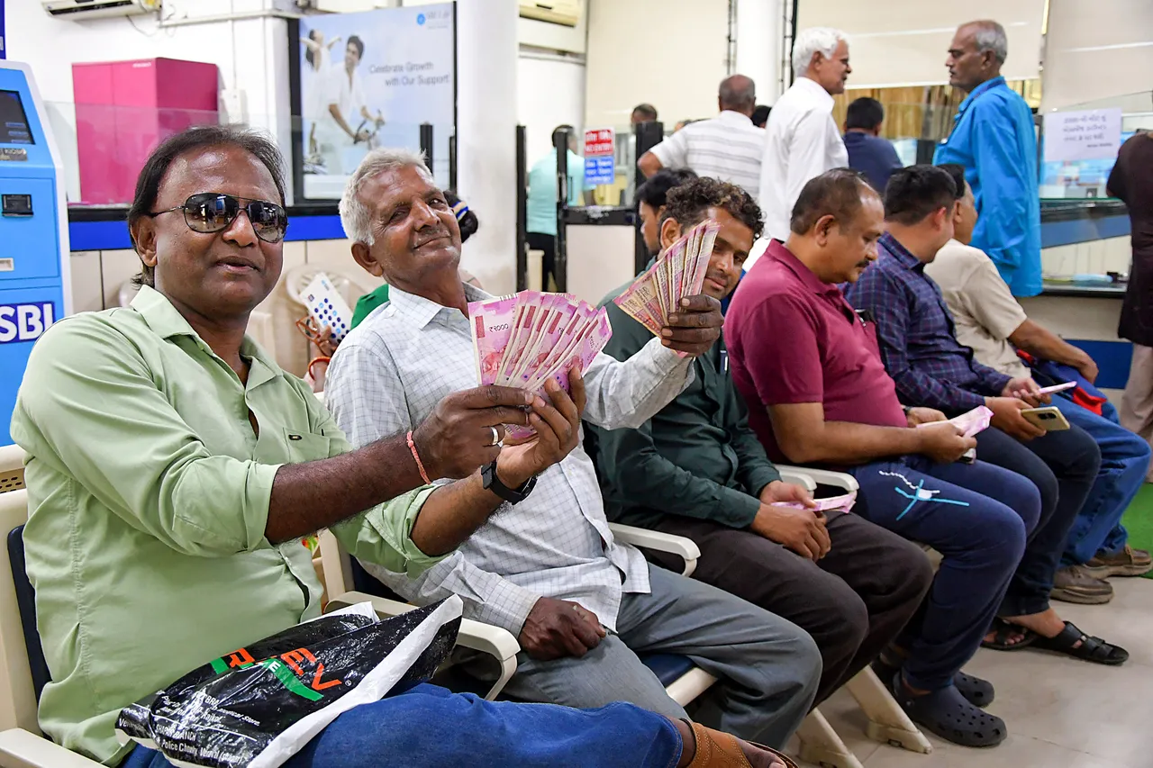 People show their Rs 2,000 notes at a bank, in Rajkot,