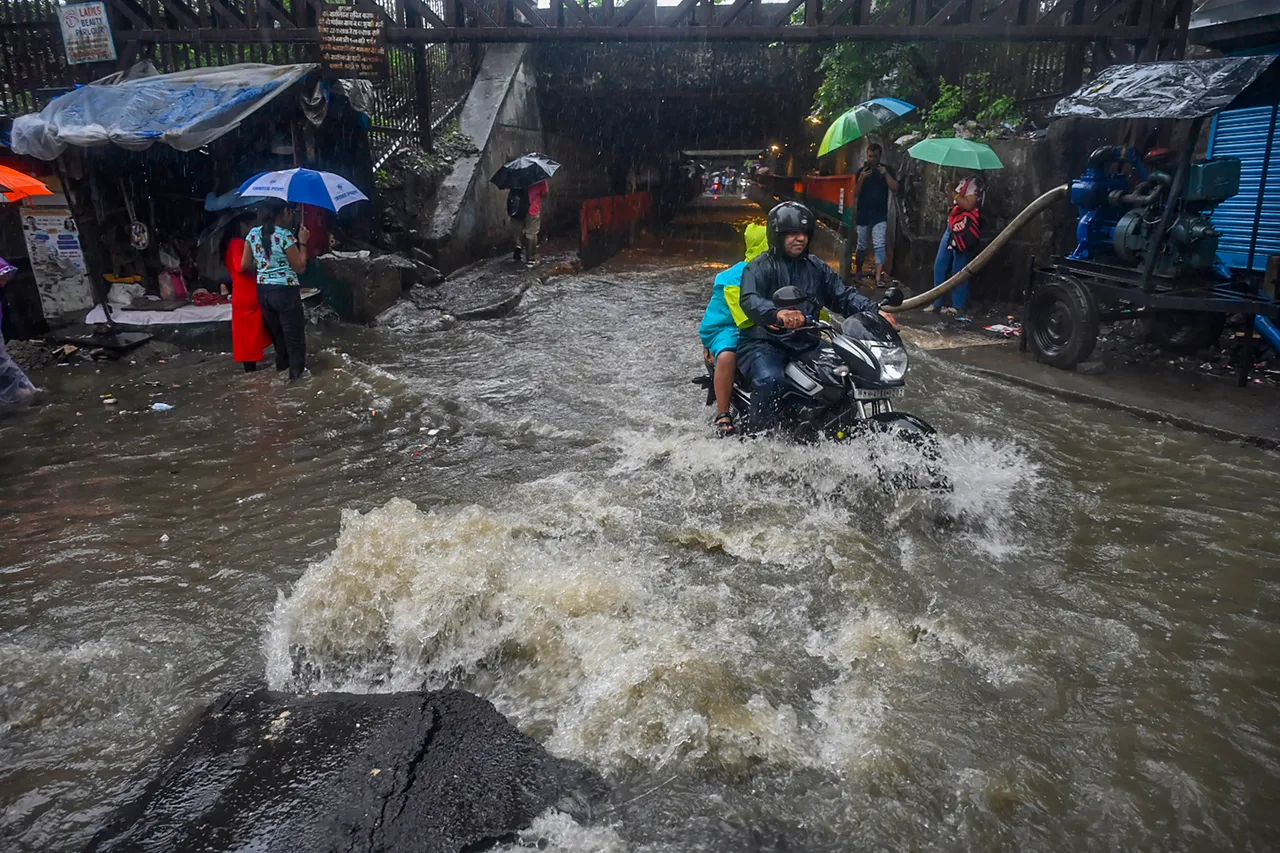 Commuters on a waterlogged road amid rain in Mumbai
