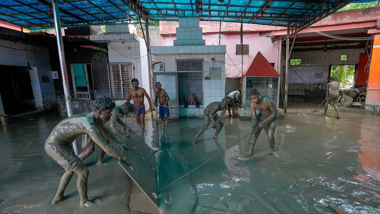 People remove mud and silt from a temple as floodwater of the swollen Yamuna river continues to recede, at Yamuna Ghat in New Delhi