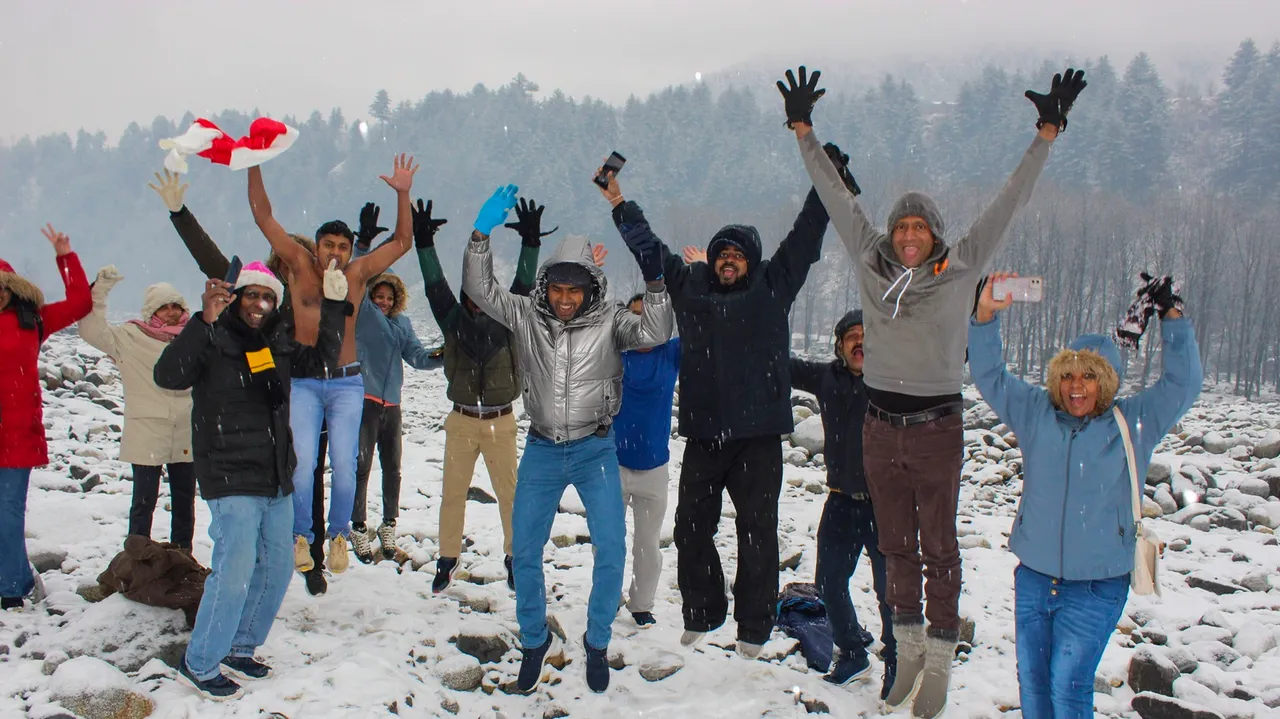 Tourists play with snow during snowfall, in Manali