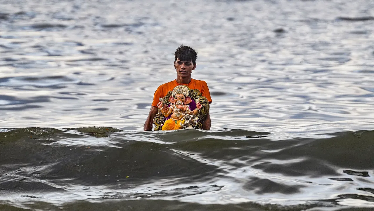 A volunteer carries an idol of Lord Ganesha for immersion in the Arabian Sea during the seventh day of Ganesh Chaturthi festival, in Mumbai
