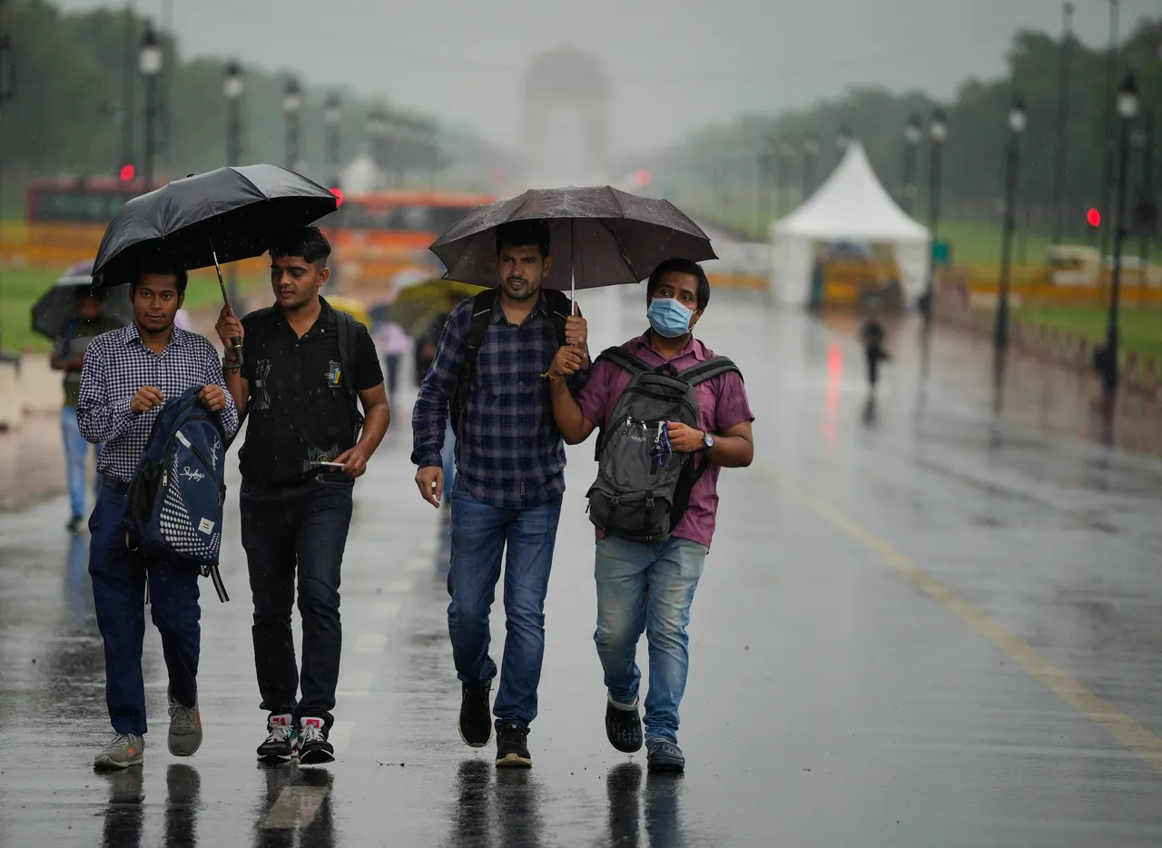 People holding umbrella walk on the Kartavya Path amid monsoon rains, in New Delhi