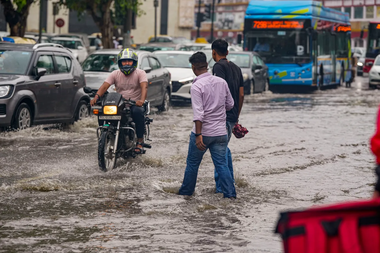 Commuters pass through a waterlogged road amid monsoon rains, in New Delhi
