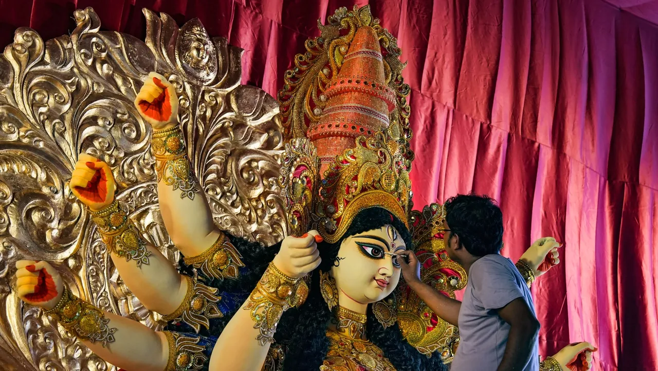 An artist gives final touches to the idol of Goddess Durga at a pandal ahead of Durga Puja festival, in Kolkata