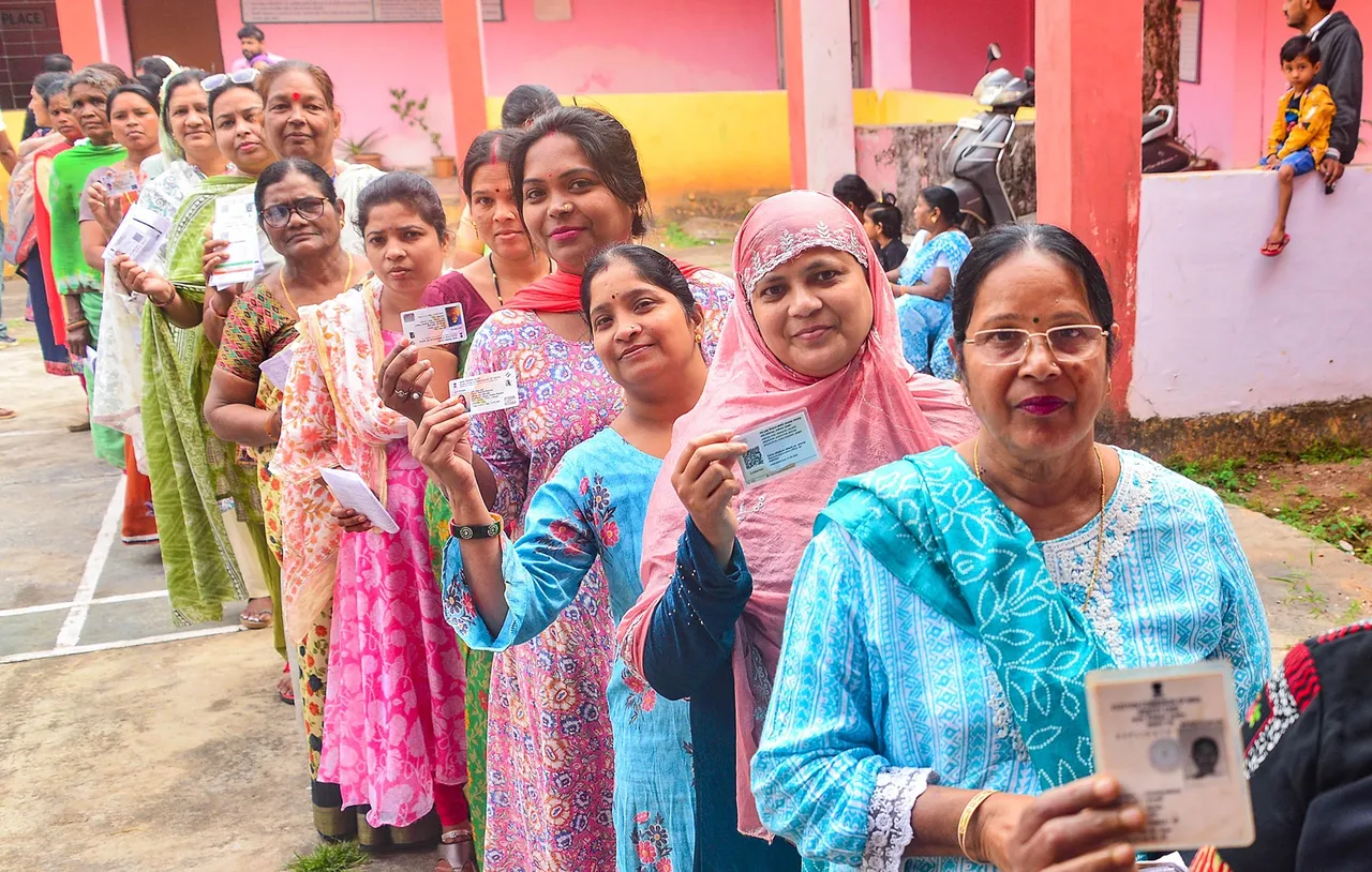 Voters show their identification cards as they wait in a queue to cast their votes for the 1st phase of Chhattisgarh Assembly elections, at a polling station in Jagdalpur, Bastar district