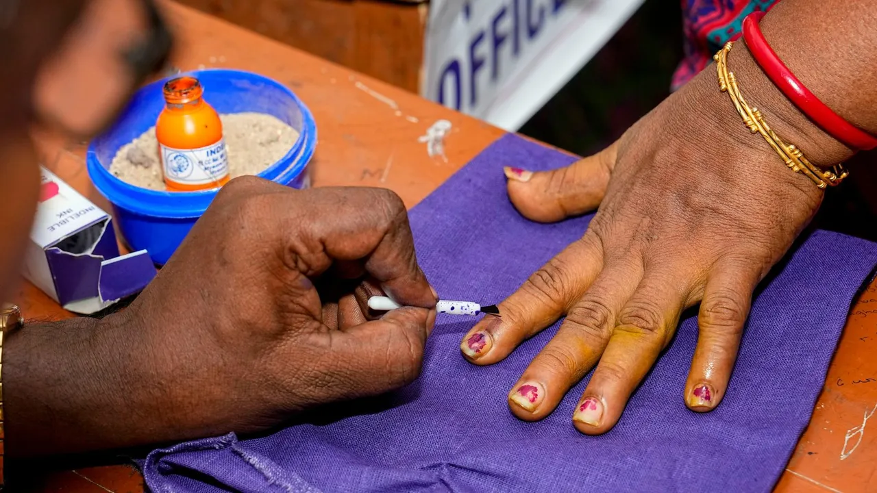 A polling official marks a voter's finger with indelible ink before she casts her vote for the first phase of Lok Sabha elections, in Sonitpur, Friday, April 19, 2024