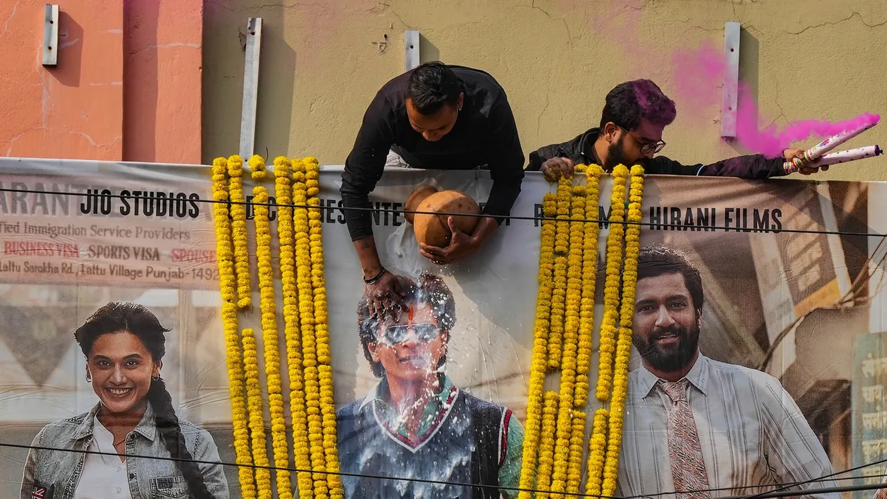 A fan of Shah Rukh Khan pours milk on his poster before the screening of the first show of 'Dunki' movie, in Kolkata