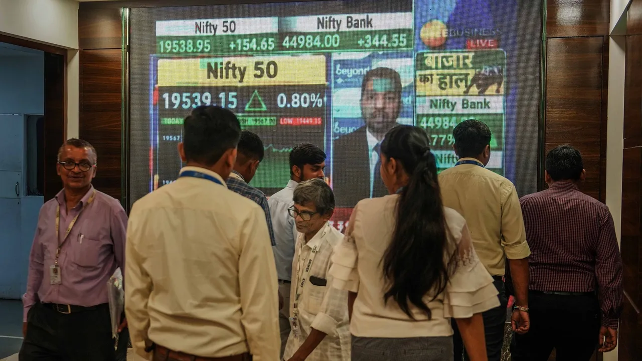People walk past a digital display outside the Bombay Stock Exchange (BSE), in Mumbai