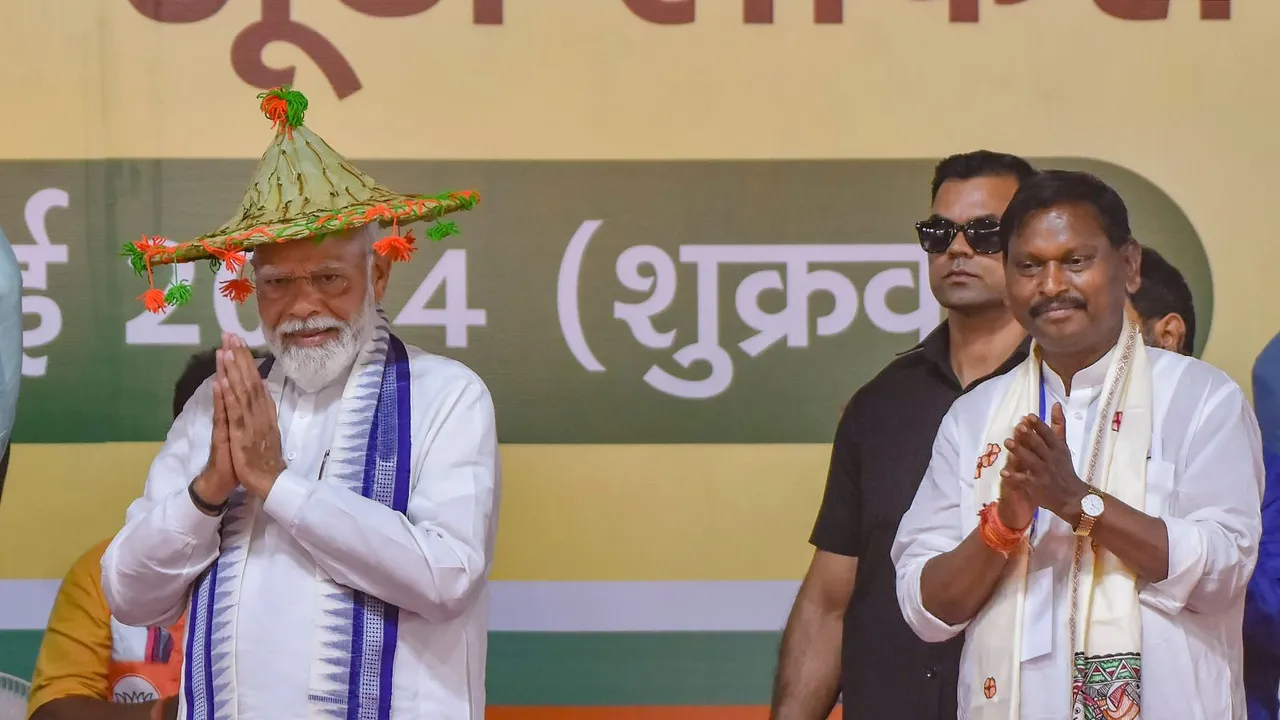 Prime Minister Narendra Modi, with Arjun Munda, wearing a traditional 'Hat' greets during a public meeting for Lok Sabha elections, in West Singhbhum, Friday, May 3, 2024