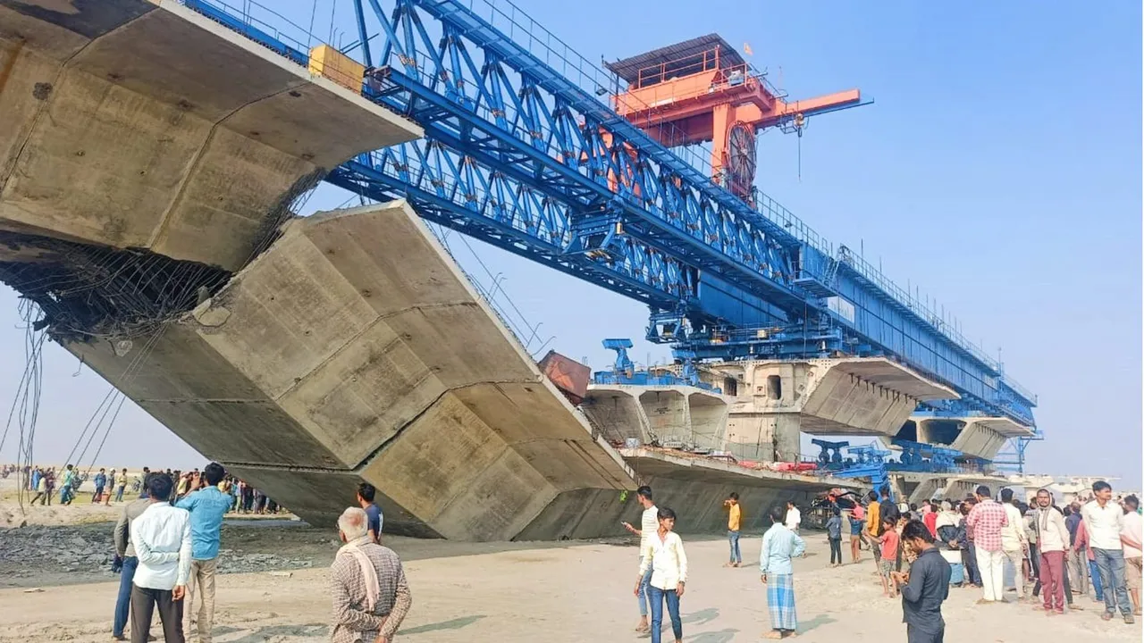 People stand near the collapsed portion of an under-construction bridge being built over the Koshi river, in Supaul