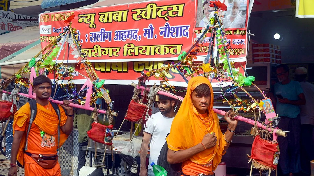 Kanwariyas walk past a shop on which banners with shopkeeper's name was put up on Kanwar Marg after an order issued by Uttar Pradesh Government, in Muzaffarnagar, Saturday, July 20, 2024.