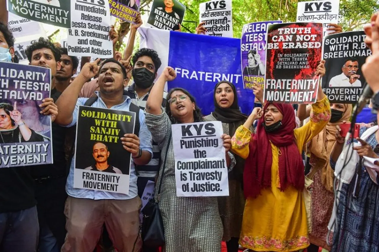 People hold placards and shout slogans during a protest against the arrest of social activist & journalist Teesta Setalvad