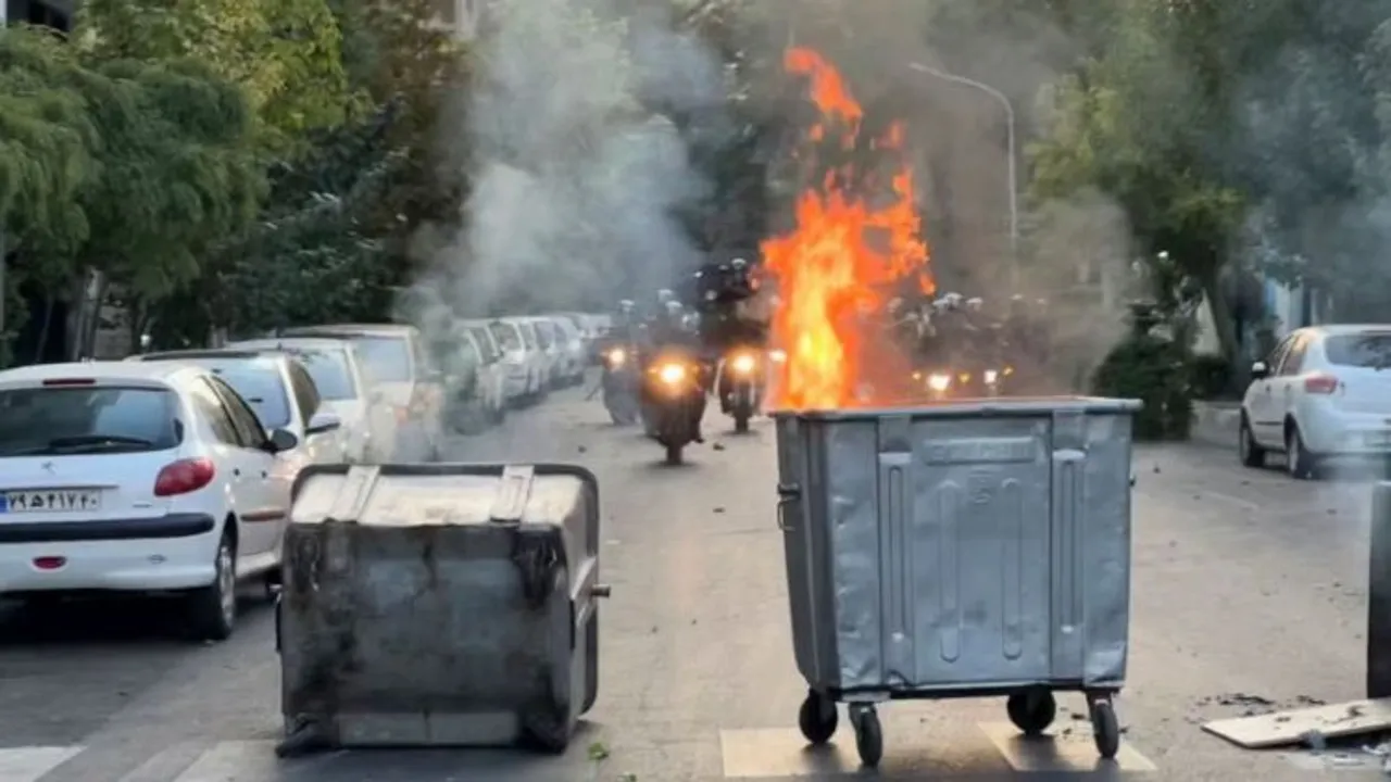 Photo taken by an Iranian protestor, a trash bin is burning as anti-riot police arrive during a protest over the death of a young woman who had been detained for violating the country's conservative dress code, in downtown Tehran, Iran. 