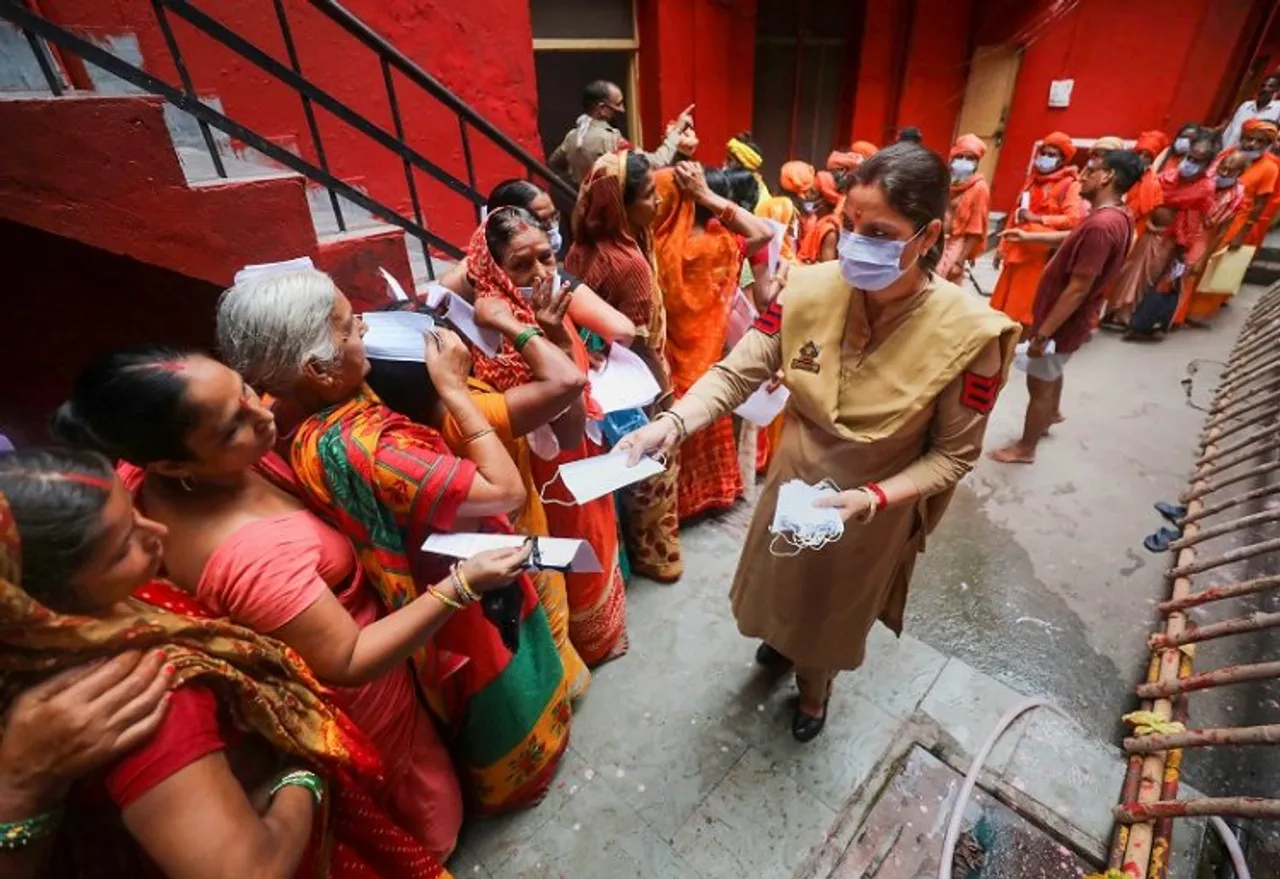 Pilgrims receive face masks from a policewoman as they wait in a queue to get themselves registered for the Amarnath Yatra 2022, at Ram Mandir base camp, in Jammu