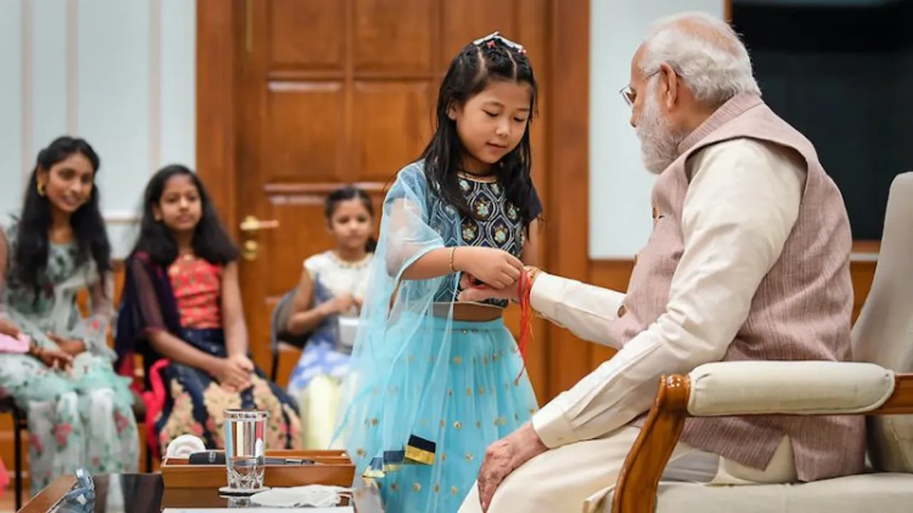 A girl ties rakhi on the wrist of Prime Minister Narendra Modi during Raksha Bandhan celebrations, in New Delhi, Thursday