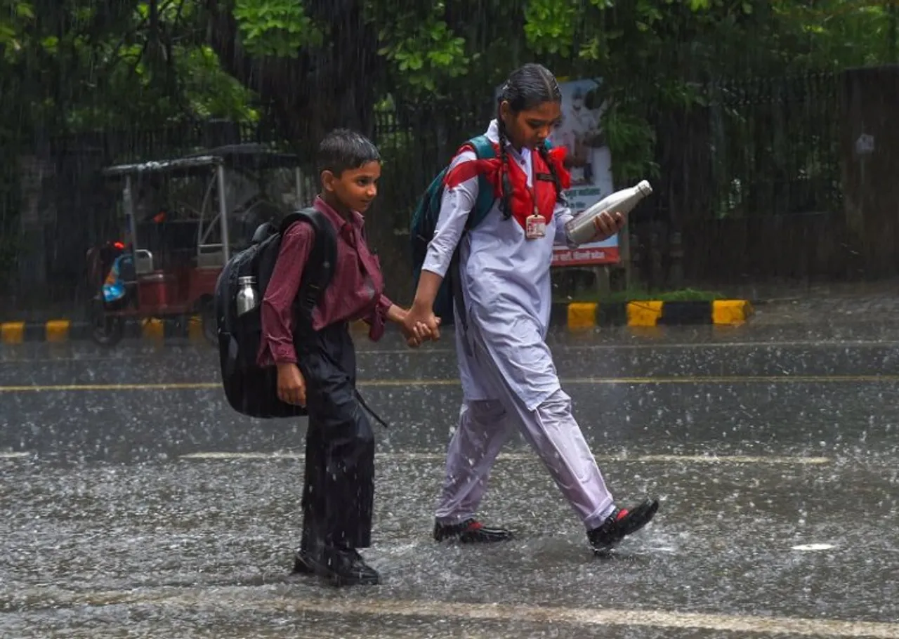 School children walk down a road amid monsoon rain, in New Delhi