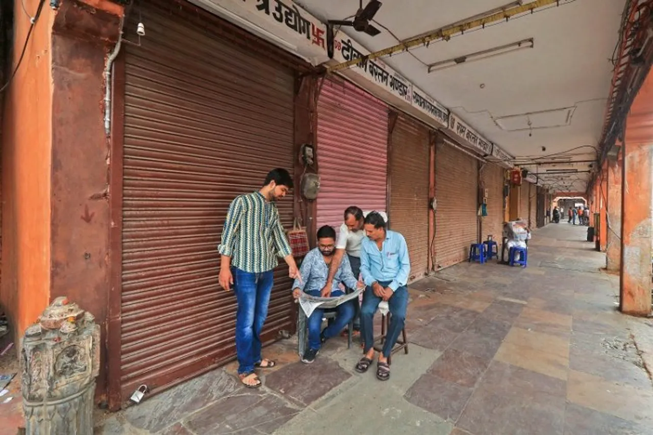 Locals read a newspaper at a deserted market during a bandh called by various Hindu organisations over the murder of tailor Kanhaiya Lal in Udaipur, in Jaipur