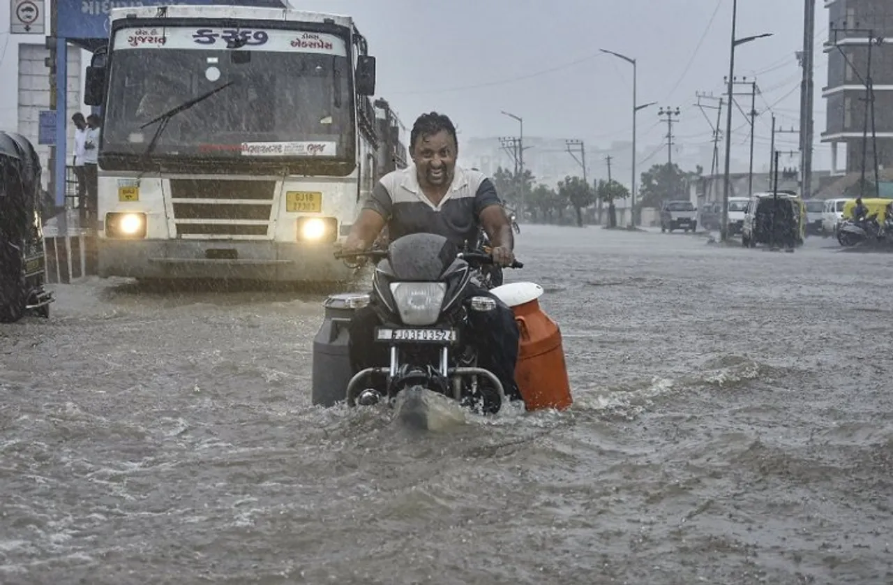 A man riding a motorcycle wades through the waterlogged Ring Road after monsoon rains, in Rajkot