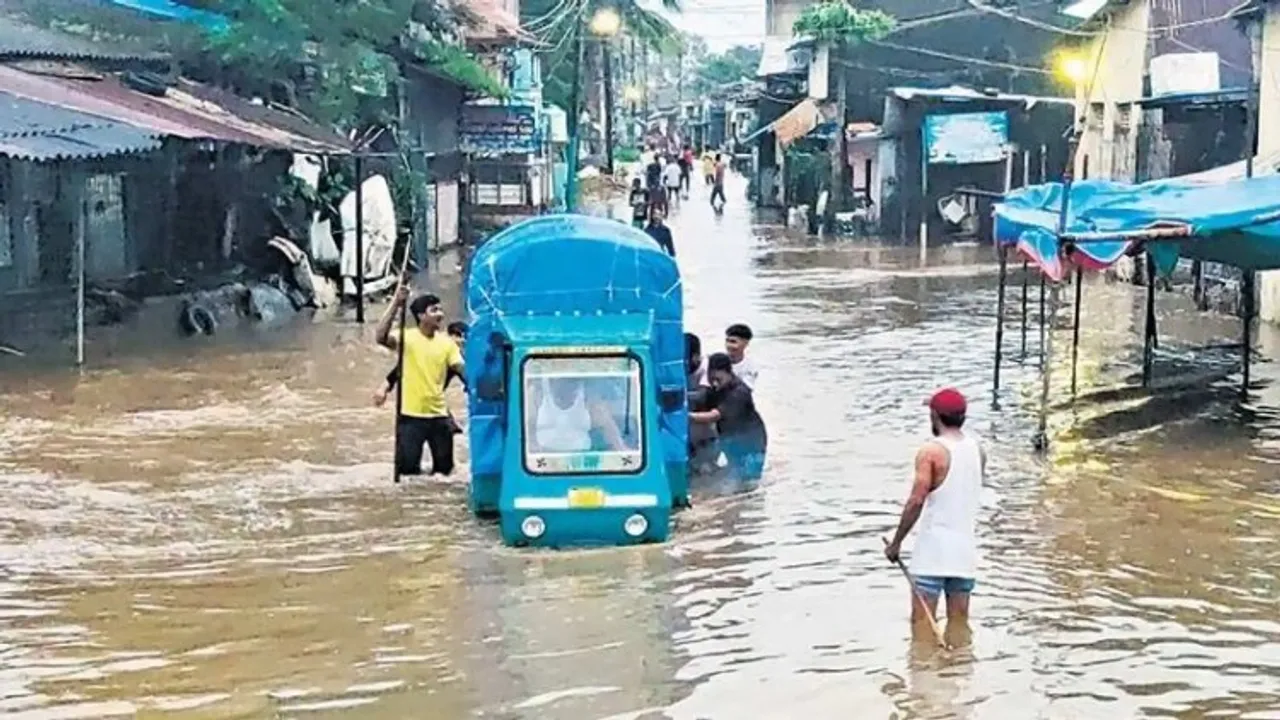 People push a vehicle through a flooded area near Purna river following heavy rainfall, in Gujarat