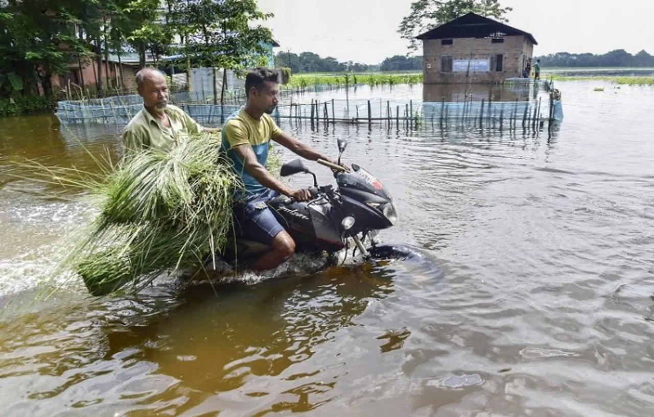  A motorcyclist wades through a flooded road, in Kamrup district of Assam