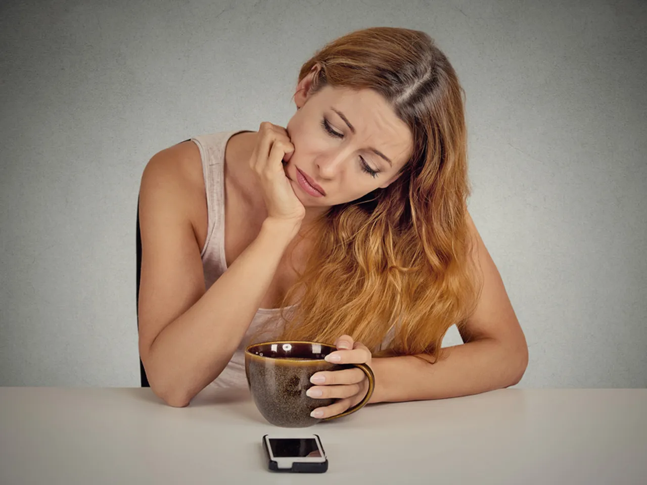A Sad girl with a coffee mug and an iPhone
