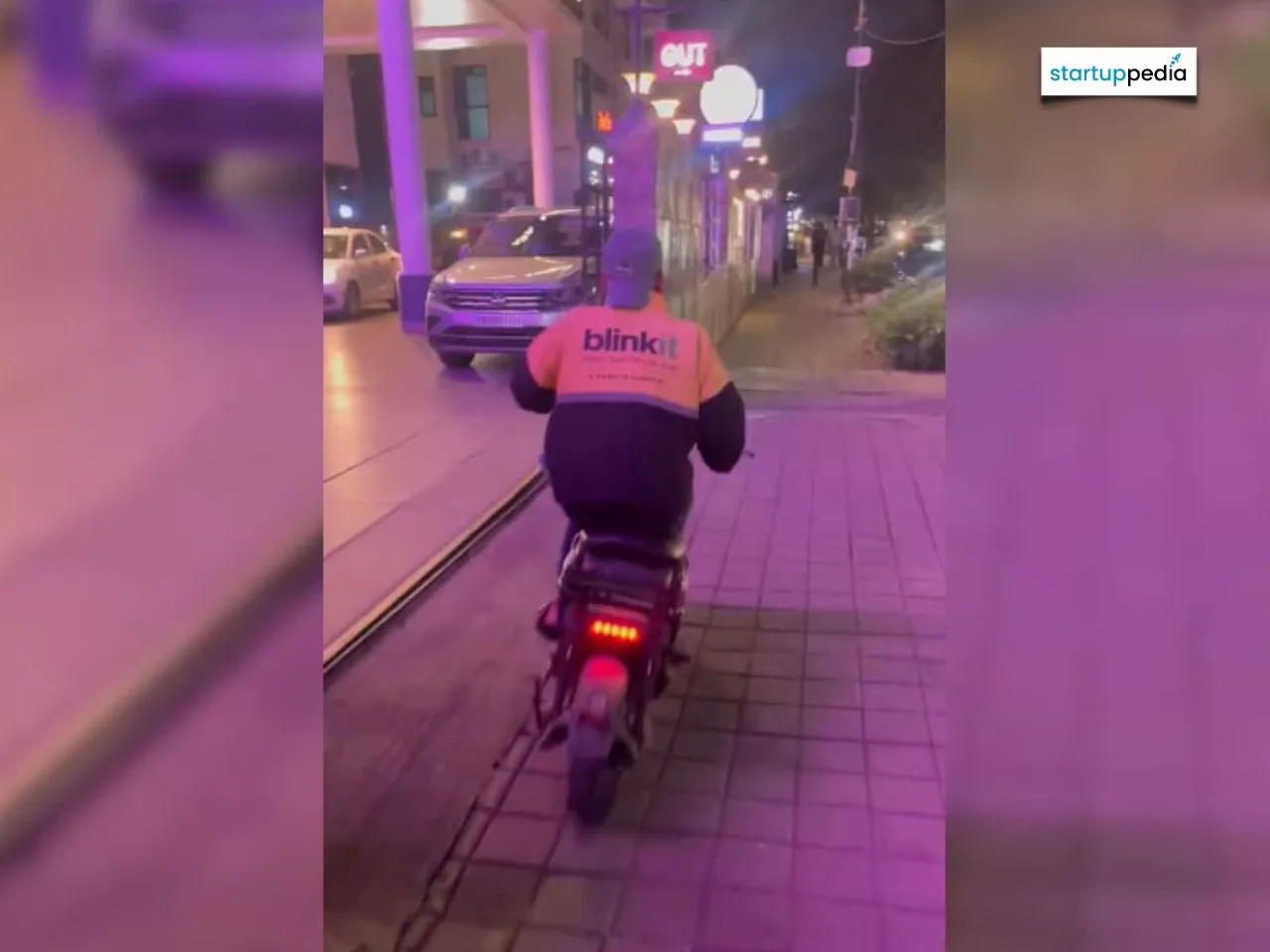 Blinkit delivery man driving on a footpath in Bengaluru 