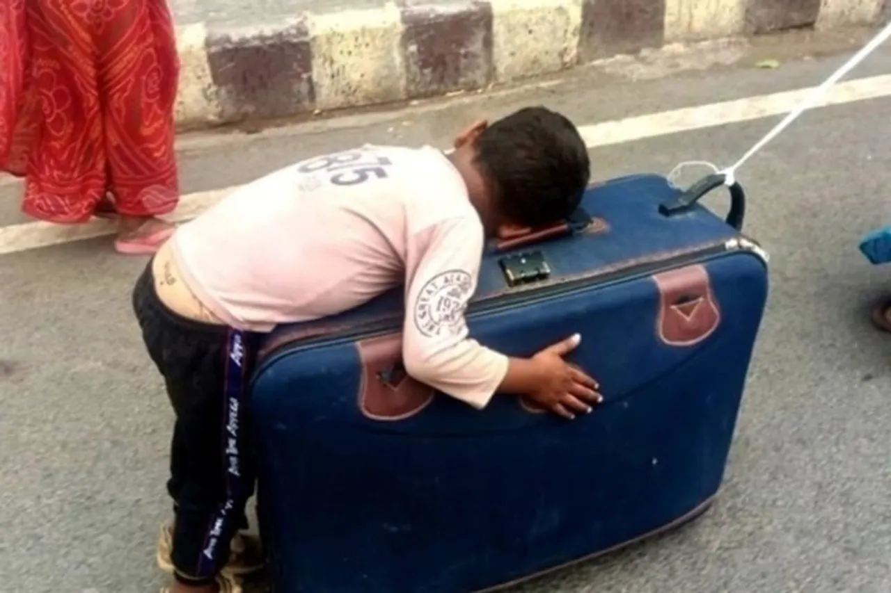 Migrant mother carries her son as he sleeps on her suitcase - viral video