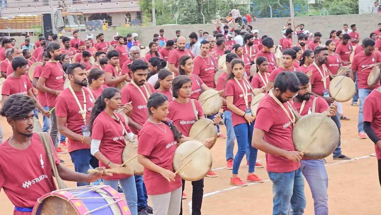 Performers stand and play drums in the shape of the number 1330