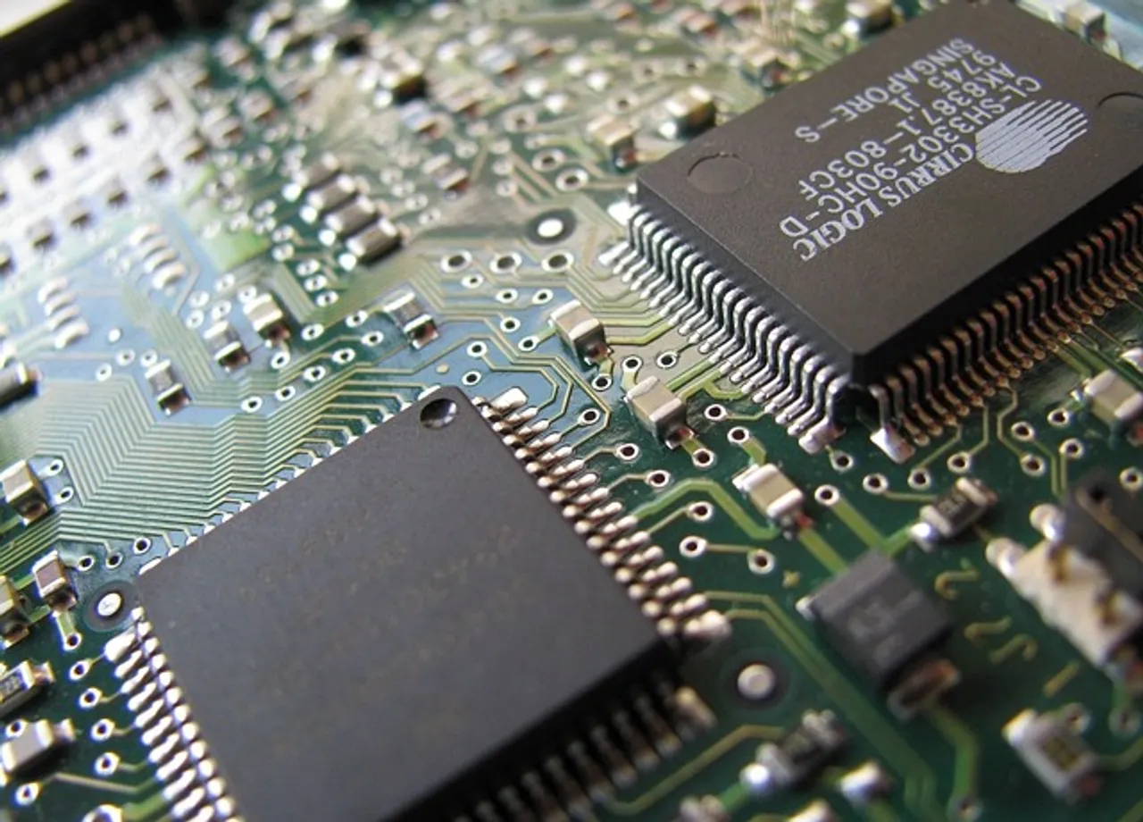 A close-up photo of a circuit board with various electronic components soldered onto it, including black rectangular chips, gold capacitors, and gray inductors. 