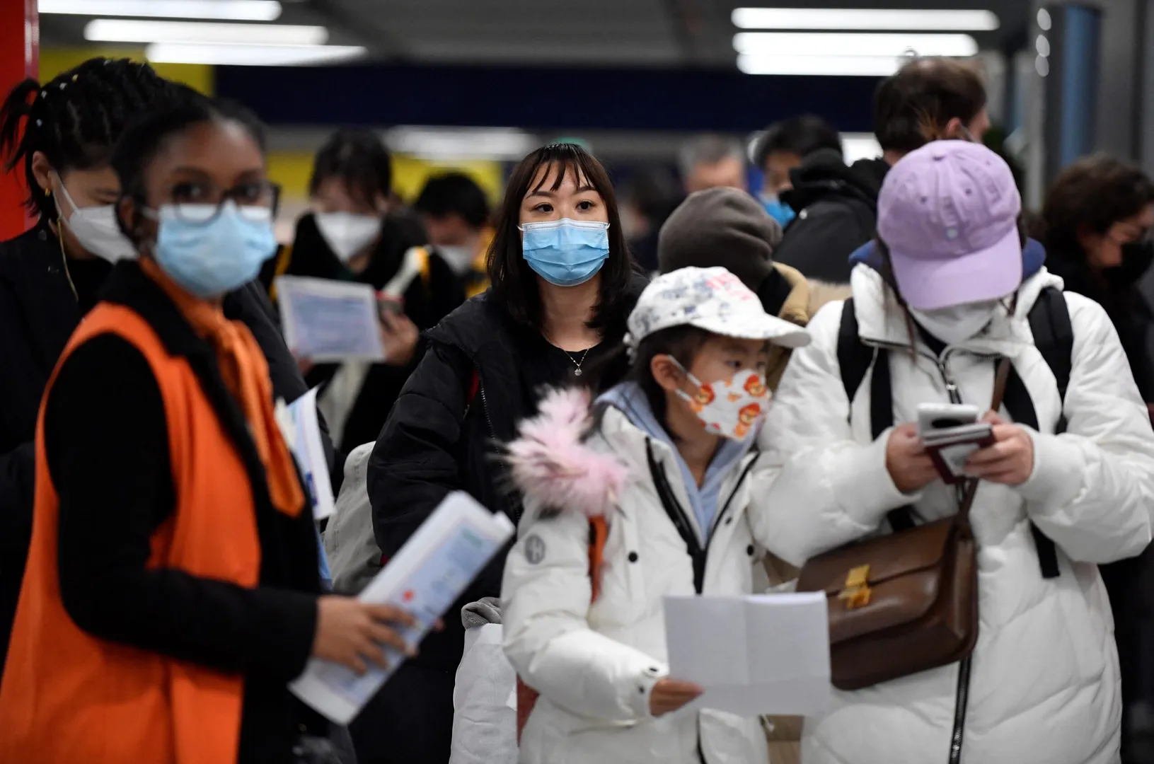Passengers of a flight from China wait in a line for checking their COVID-19 vaccination documents as a preventive measure against the Covid-19 coronavirus, after arriving at the Paris-Charles-de-Gaulle airport in Roissy, outside Paris, on January 1, 2023. - France and Britain on December 30 joined a growing list of nations imposing Covid tests on travellers from China, after Beijing dropped foreign travel curbs despite surging cases -- and amid questions about its data reporting.