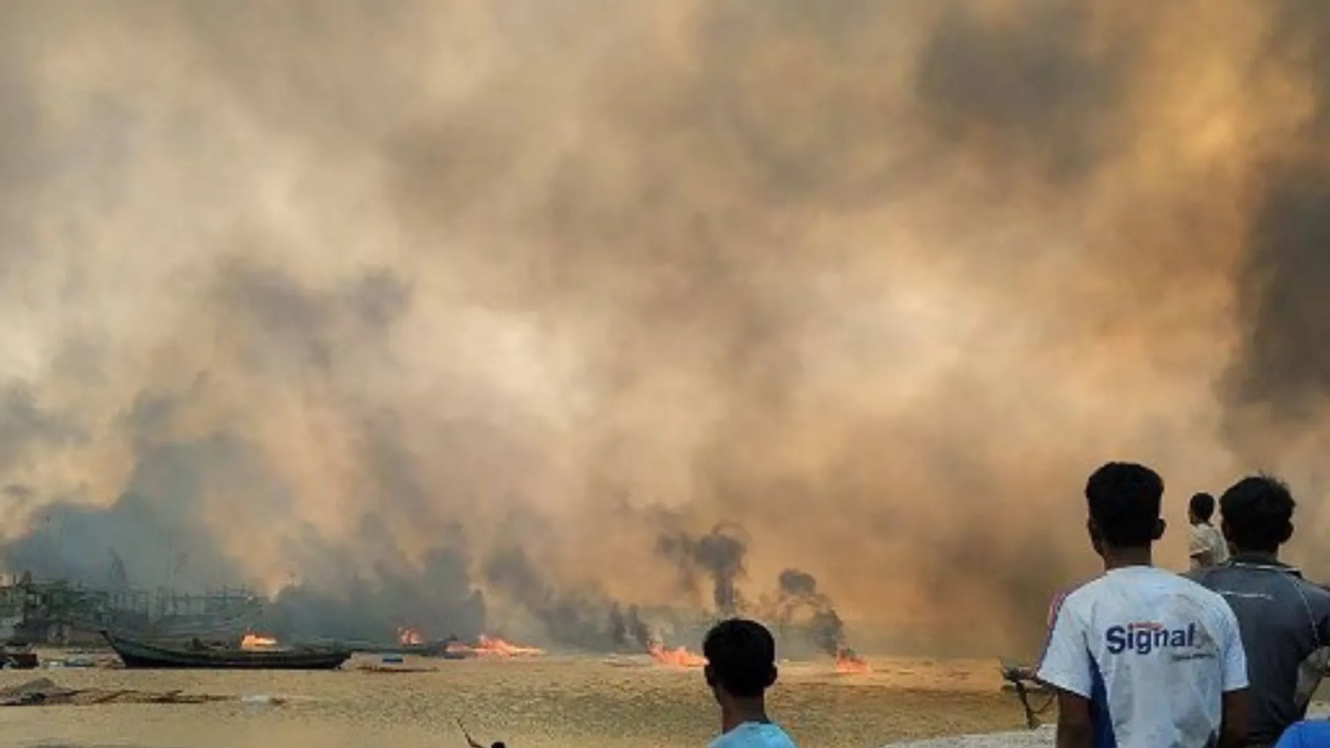 This photo from Jan 9, 2025, shows people looking at burning homes at the site of a suspected air strike carried out by Myanmar's military at Kyauk Ni Maw village.