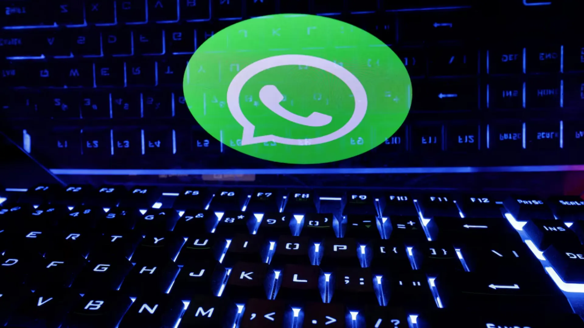 A keyboard is placed in front of a displayed WhatsApp logo in this illustration.