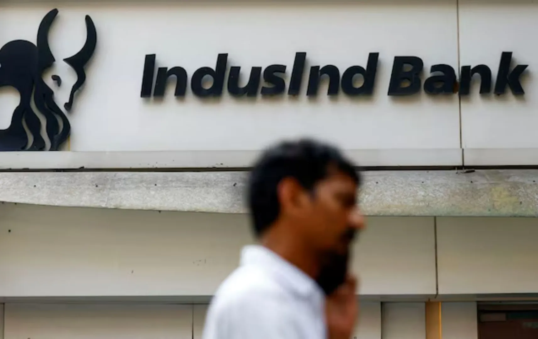 A man walks outside a branch of IndusInd Bank in New Delhi, India