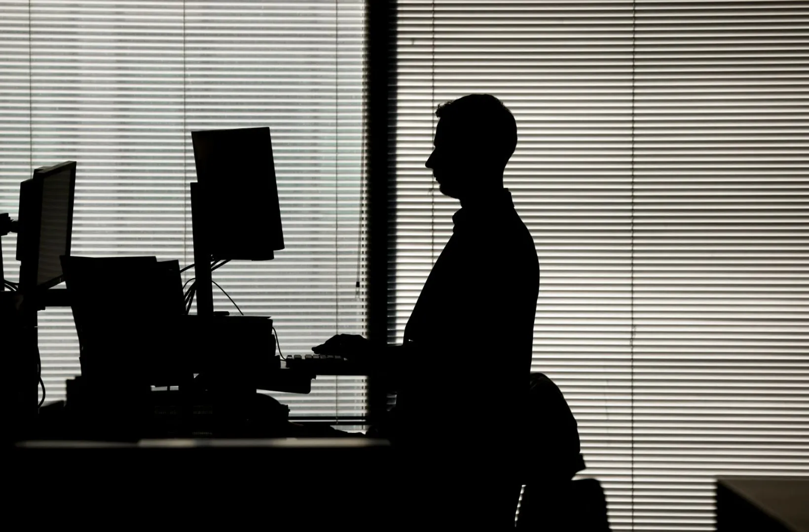  man works at a computer on a standing desk in an office
