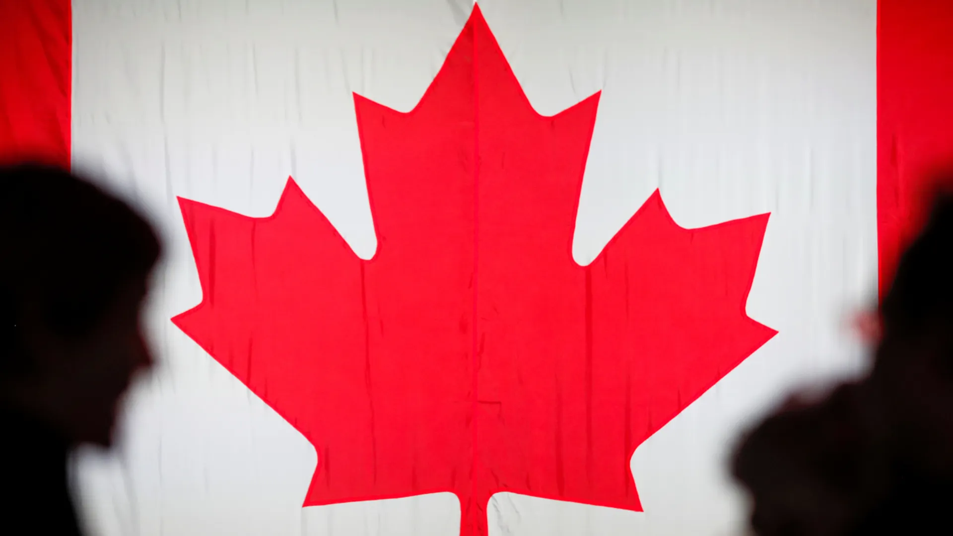 File Photo: People are silhouetted in front of the Canadian national flag in Montreal, Quebec, Canada October 21, 2019. 