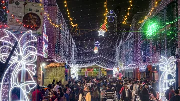 People at Anglo Indian community's residential area Bow Barracks which is decorated with lights on Christmas eve, in Kolkata, Tuesday, Dec. 24, 2024.