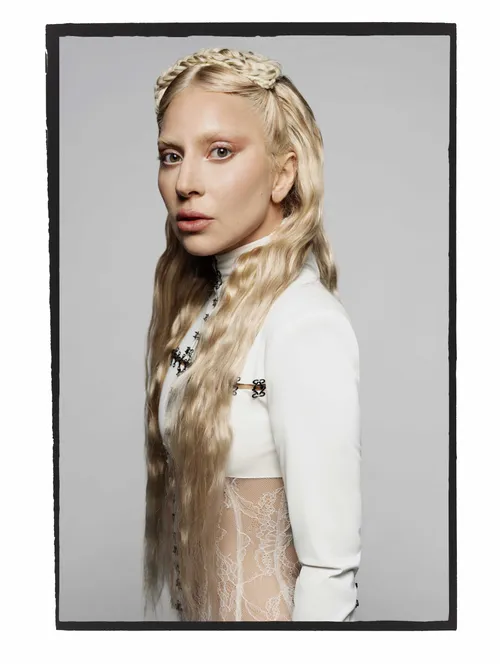 a woman with long blonde hair styled in braids wearing a white dress with lace detailing