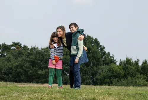three children posing closely together outdoors