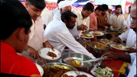 Men grabbing food at a wedding reception in Pakistan