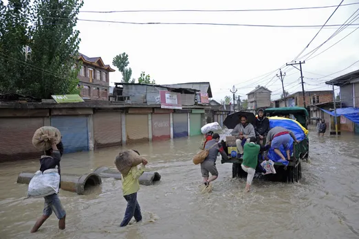 Non-local workers hurry to board a truck crossing a flooded road in Srinagar city, Kashmir.