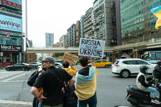 back view of people in street holding signs against the war in ukraine