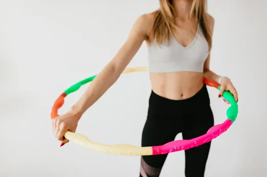 crop slim sportswoman with colorful hula hoop