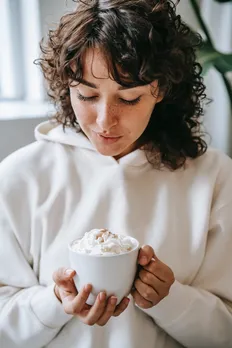 woman blowing on coffee with whipped cream