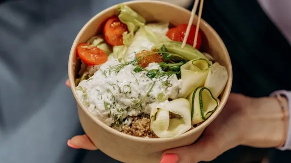 person holding a bowl with vegetable salad