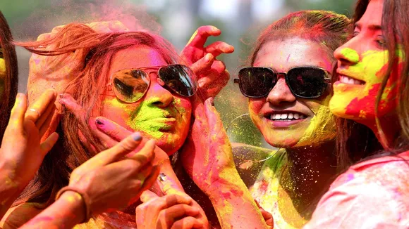 Women smear colours on each other's faces during pre-Holi celebrations