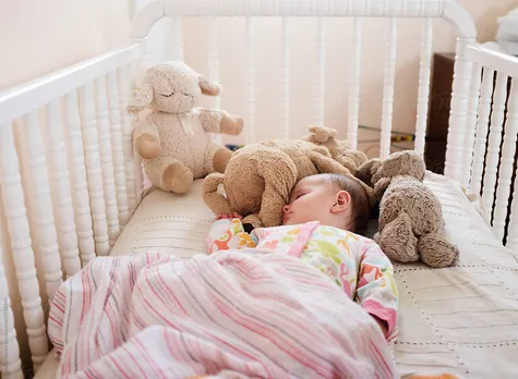 Baby Sleeping In Crib With Stuffed Toys