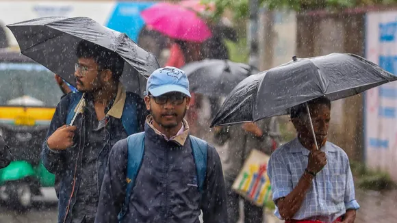 People holding umbrellas commute amid rains due to Spawn cyclone, in Bengaluru, Karnataka, Tuesday, Oct. 15, 2024.
